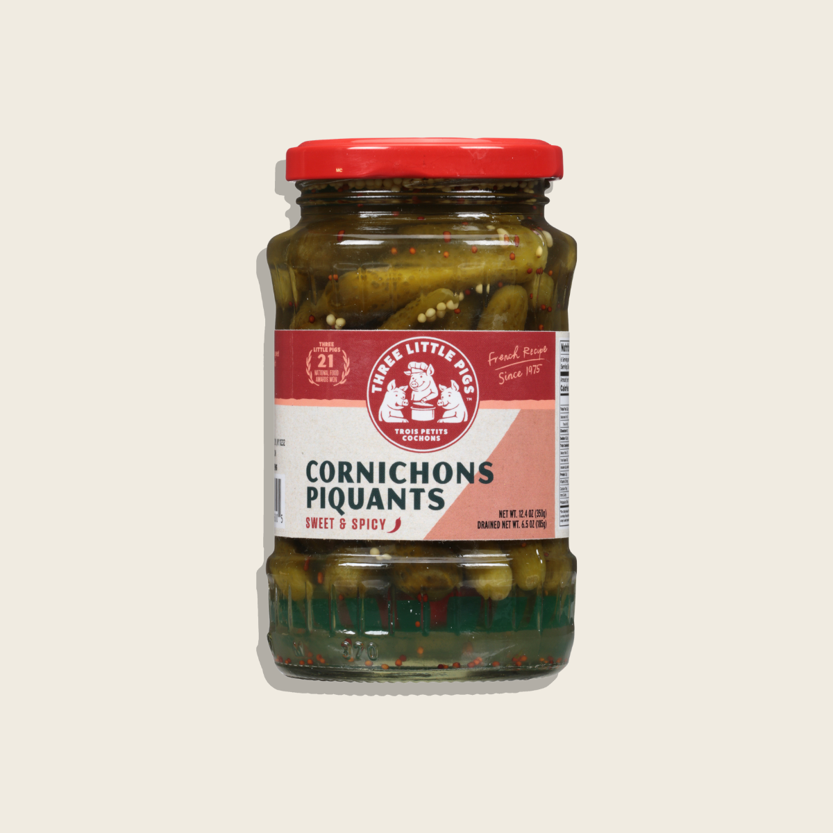 Jar of cornichons with a red lid and label on a light beige background