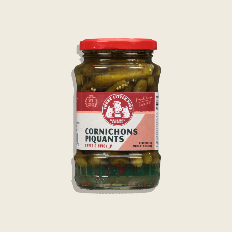 Jar of cornichons with a red lid and label on a light beige background