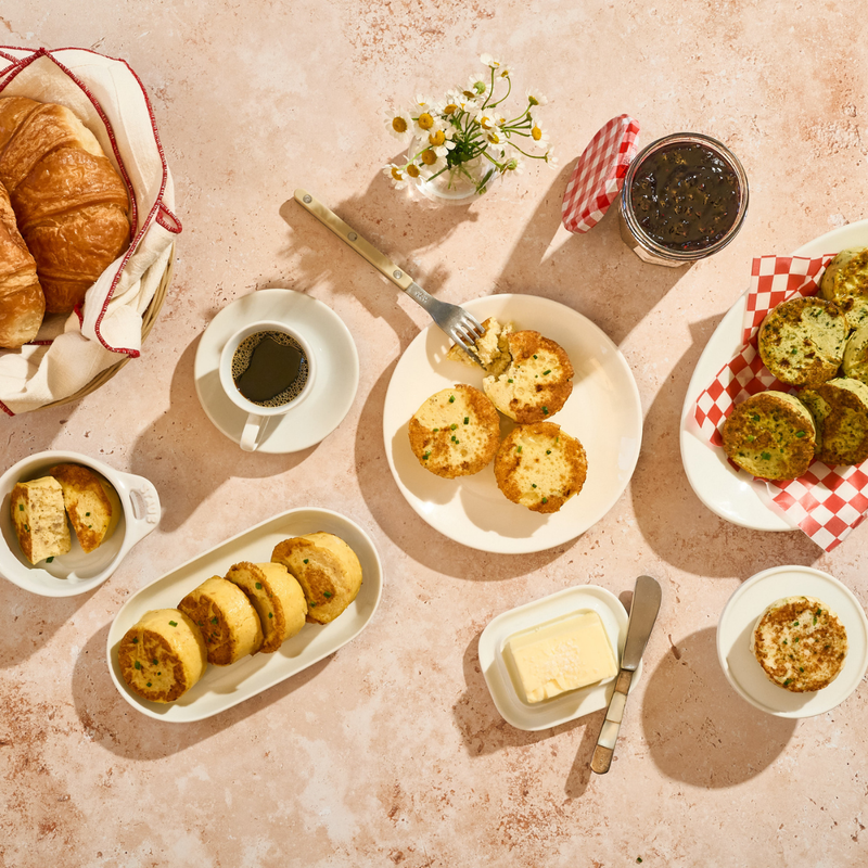 Breakfast table with pastries, coffee, and Egg Bites on a textured surface.